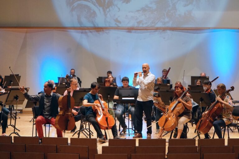 Pori Sinfoniettan konserttiharjoitukset, edessä sellistit kapellimestari Tibor Bogányi, Béla Bánfalvi, Saija Jakovaara ja Magdalena Büchert sekä huilisti Jukka-Pekka Lehto, salissa sinertävät valot ja takaseinällä heijastettuna maapallo.