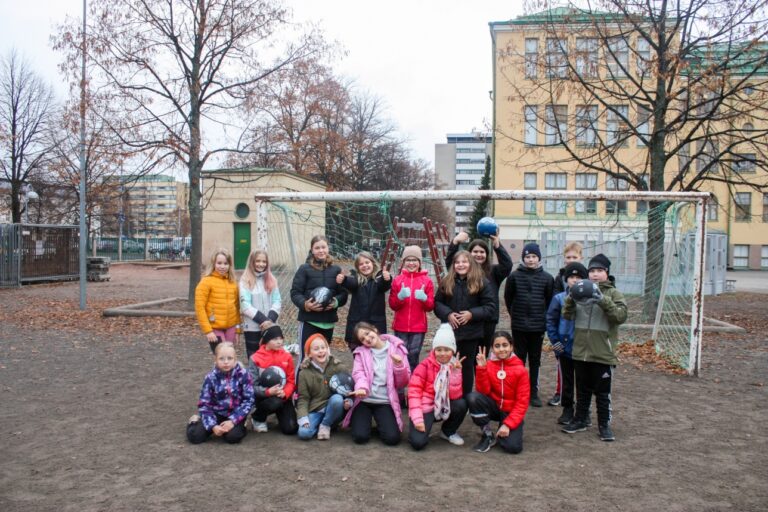 Neljännen luokan oppilaat jalkapallojen kanssa