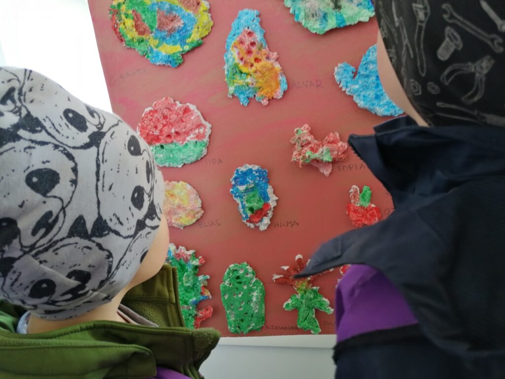 Kaksi lasta, katsovat heidän edessään olevaa taideteosta. Sisätila.