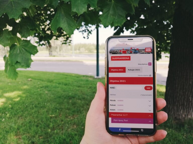 SuomiAreena 2021 ohjelma puhelimen näytöllä puiden katveessa