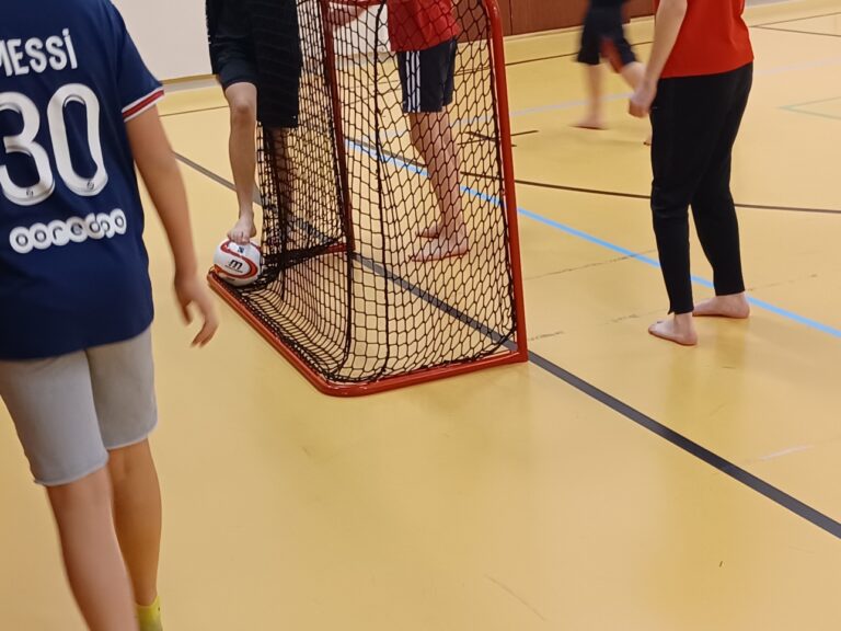 Koulun liikuntatunnilla jalkoja maalin edessä