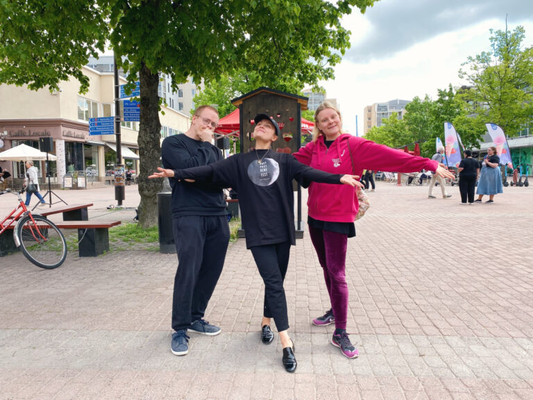 Kolme ihmistä kävelykadulla poseeraamassa