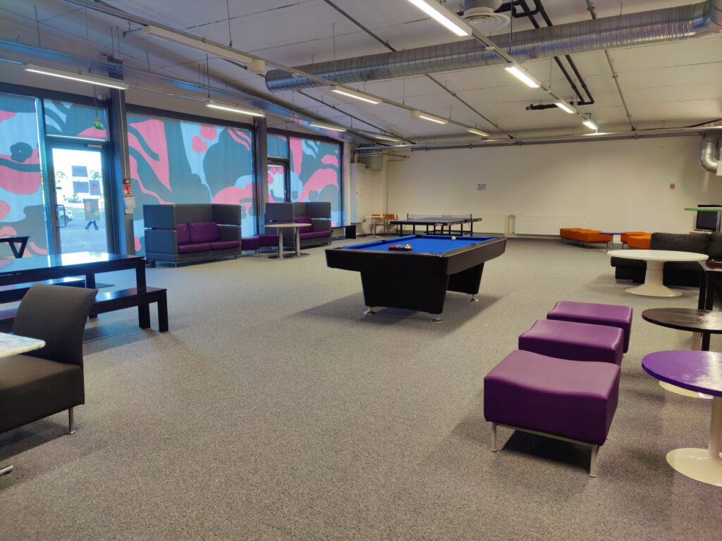 Huone jossa biljardipöytä ja violetteja istuinryhmiä