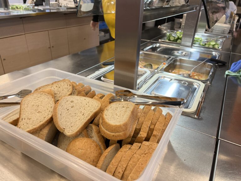 Linjasto, jonka päädyssä leipää. Taaempana keittoa ja kurkkua astioissa.