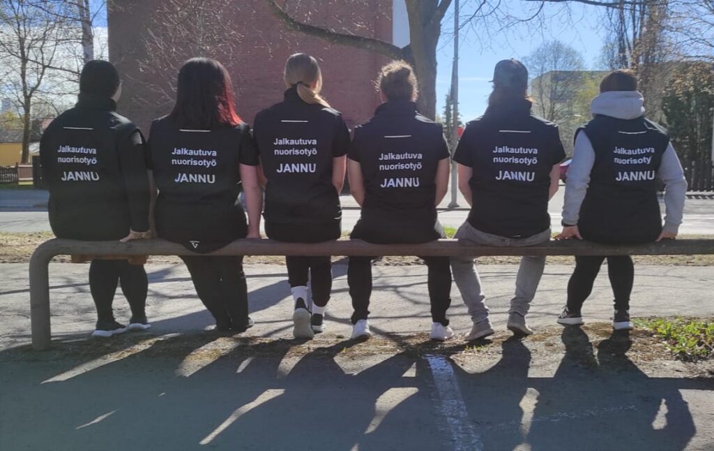 Porin jalkautuvan nuorisotyön JANNUn työntekijöitä istumassa selin penkillä