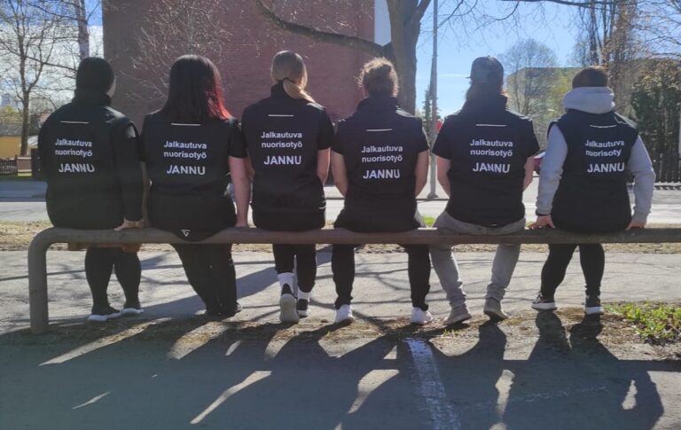 Porin jalkautuvan nuorisotyön JANNUn työntekijöitä istumassa selin penkillä