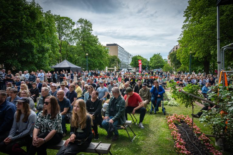 Ihmisiä istumassa penkeillä Raatihuoneenpuistossa