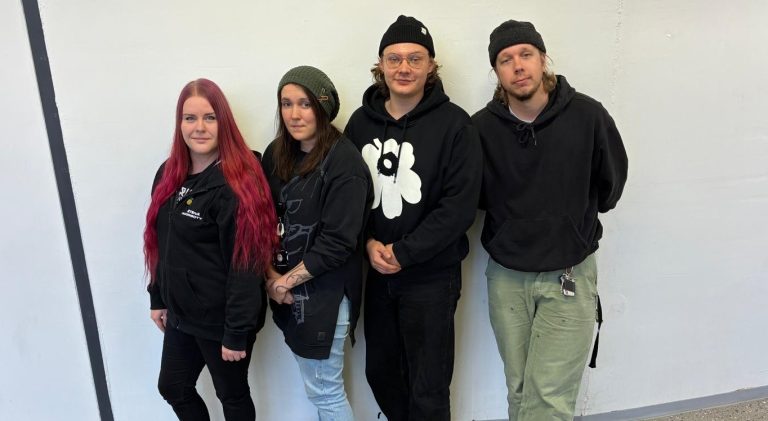 Kuvassa neljä henkilöä vaaleaa taustaa vasten.