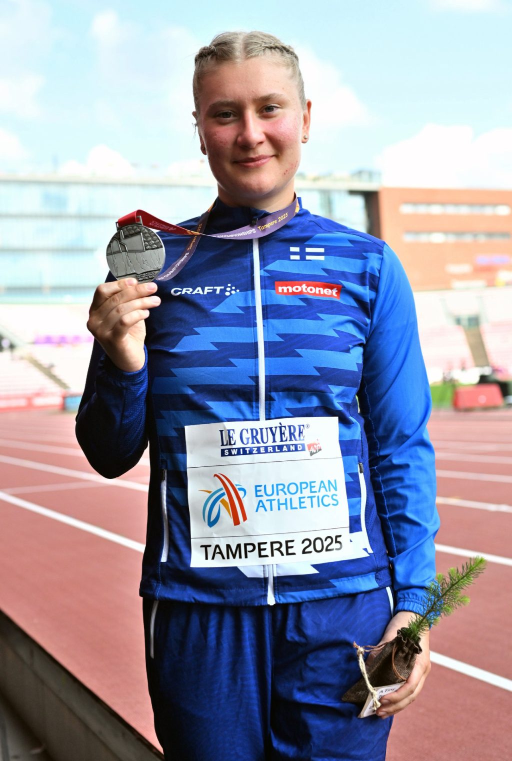 Keihäänheittäjä Rebecca Nelimarkka seisoo yleisurheilustadionilla ja pitää kädessään hopeamitalia.