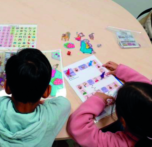 Kuvassa kaksi lasta istuu pöydän ääressä tekemässä koulutehtäviä.