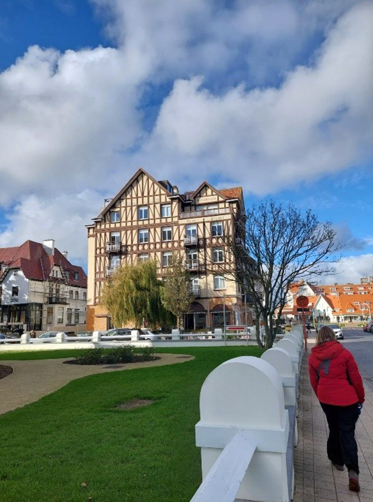 Kuva Belgiassa sijaitsevan Knokken kaupunkimaisemasta, jossa on keskeisenä elementtinä suuri, koristeellinen rakennus. Rakennus on tyyliltään perinteinen, muistuttaen tudor-tyyliä, jossa on ruskeat puurakenteet ja vaaleat seinäpinnat.