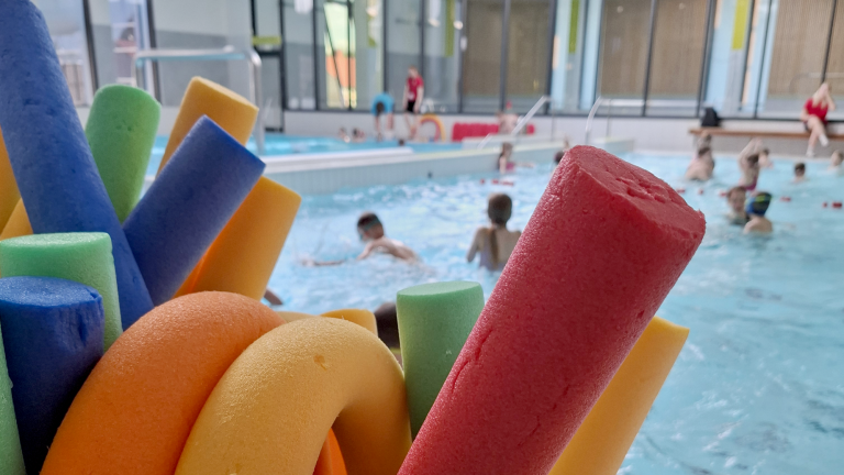 Värikkäitä uimapötkylöitä ja taustalla uima-allas