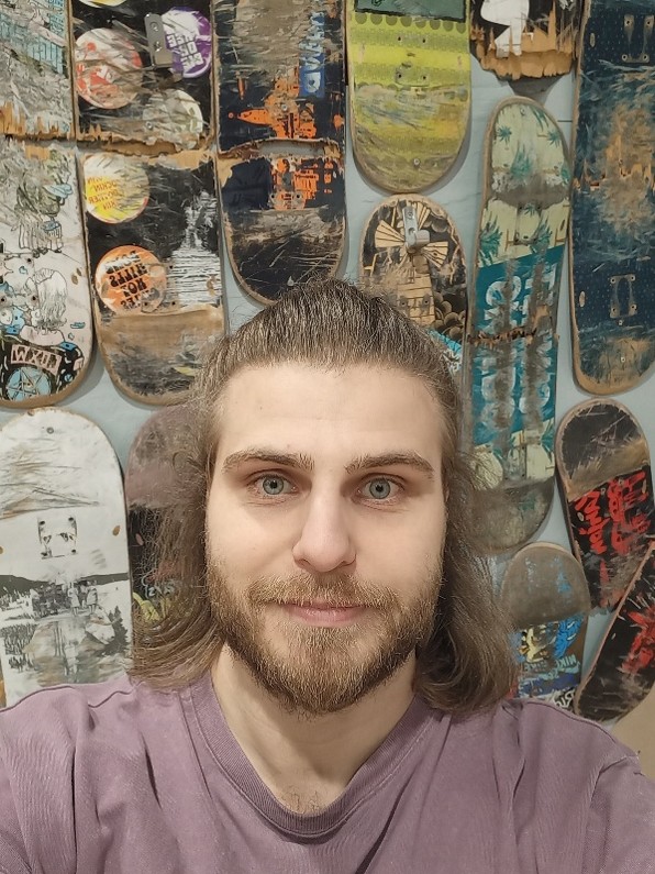 Hymyilevä mies skeittilautojen edessä