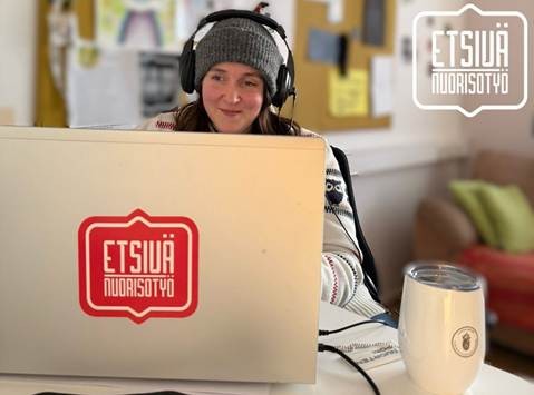 Henkilö istuu läppärin ääressä kuulokkeet korvilla