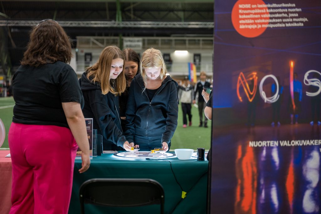 Nuoria seisoo pöydän takana ja katselee pöydällä olevaa valoa