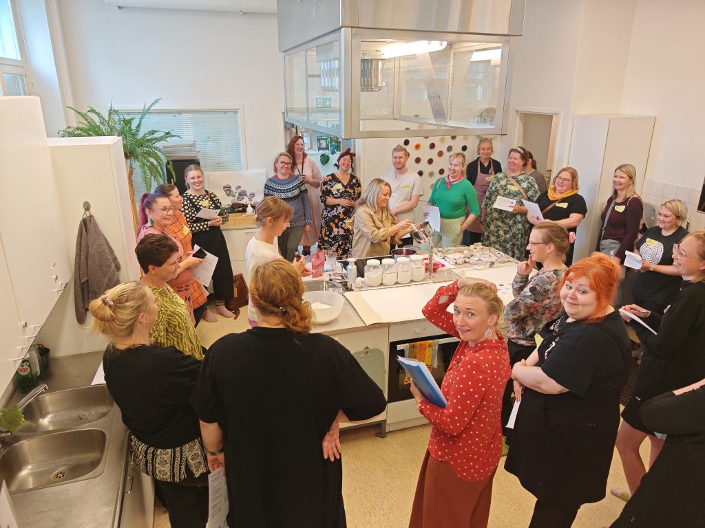 Ryhmä ihmisiä seisomassa pöydän ympärillä.