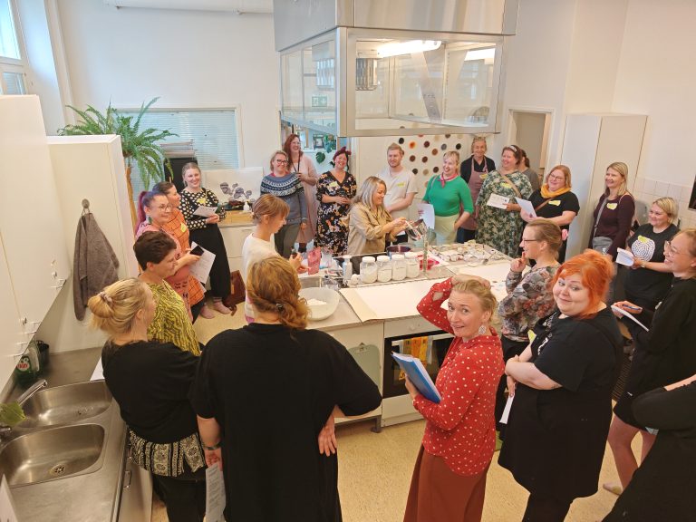 Ryhmä ihmisiä seisomassa pöydän ympärillä.