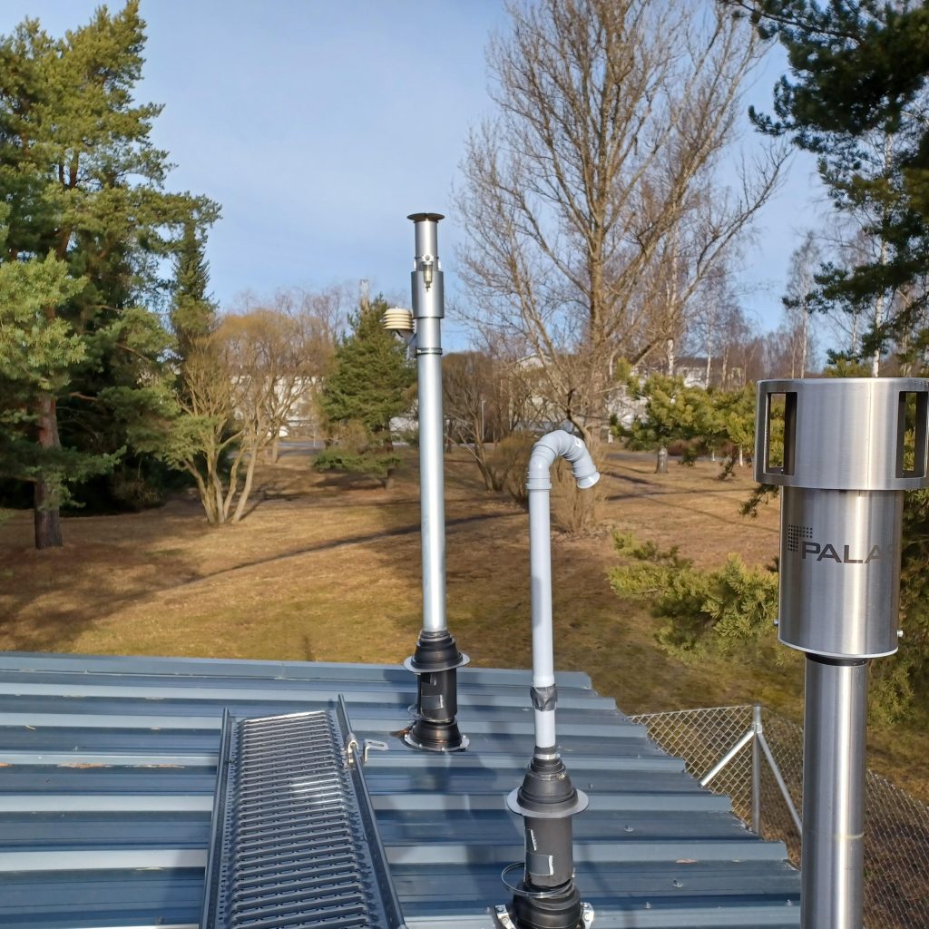 Rakennus nurmialueella, rakennuksen katolla useita putkia.