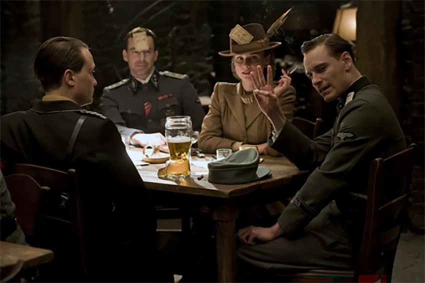 In the picture, there is three German soldiers and a woman, playing a cardgame in a pub. One of the German soldiers, is ordering three drinks.