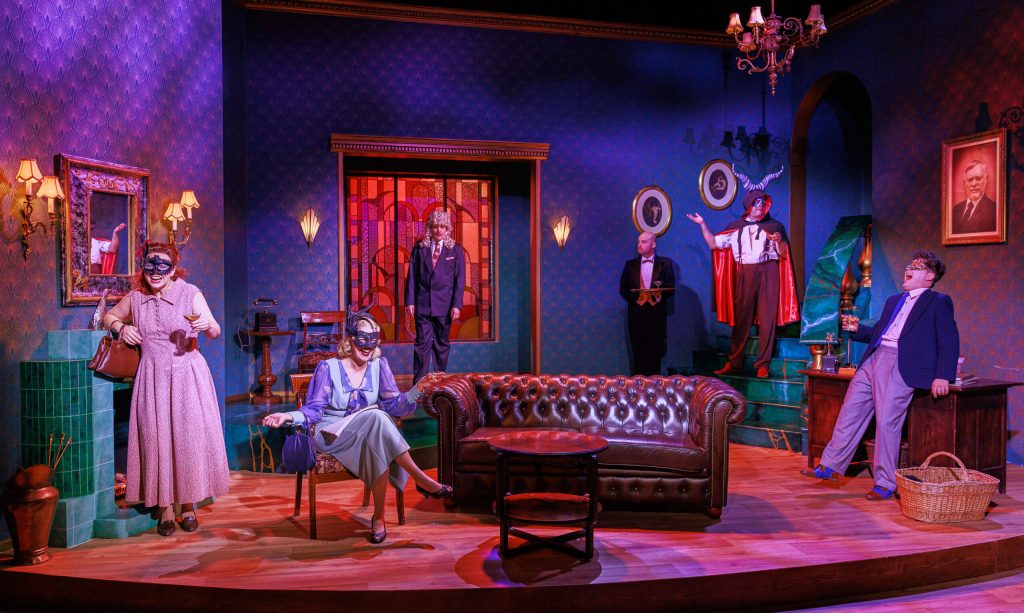 Lehdistökuva Porin Teatterin Komisario Palmun erehdys -näytelmästä. Kuvassa viisi henkilöä on saapunut Brunon juhliin. Taustalla seisoo tarjoilija tarjottimen kanssa, jossa on viinilasi.