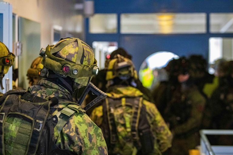 Armeijan varusteisiin pukeutuneita henkilöitä sisätiloissa.