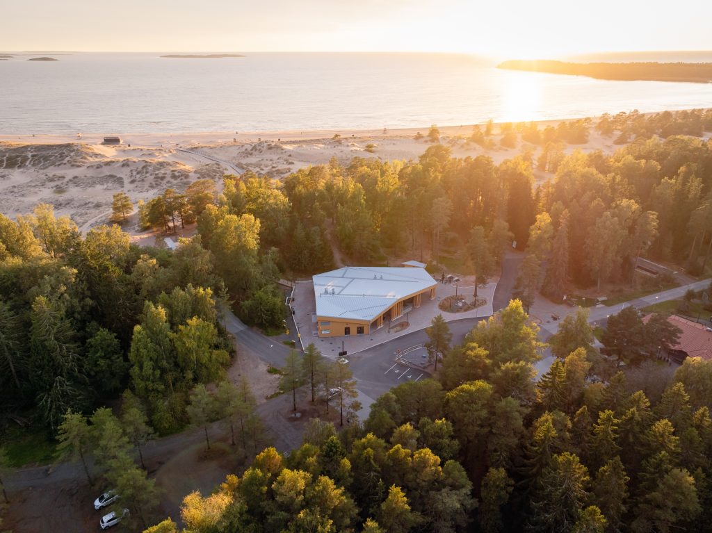 Yyterin vierailukeskus puiden keskellä ja taustalla meri auringon syleilemänä