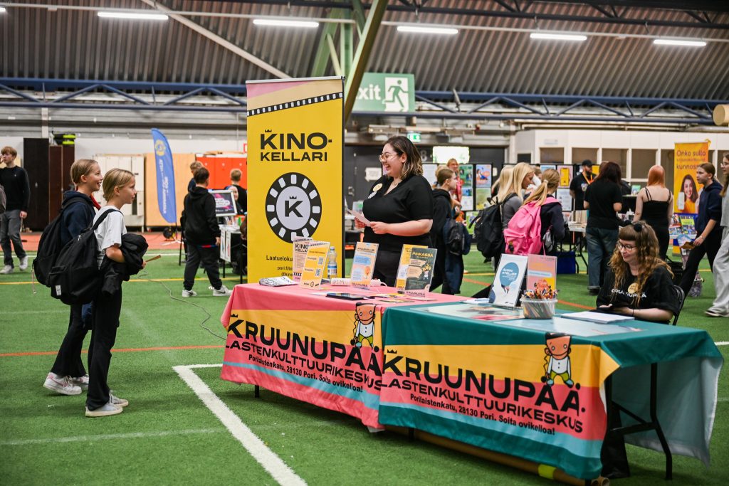 Kinokellarin esittelypisteellä hymyileviä nuoria